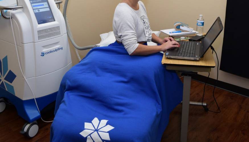 Patient comfortably doing work on computer during CoolSculpting treatment